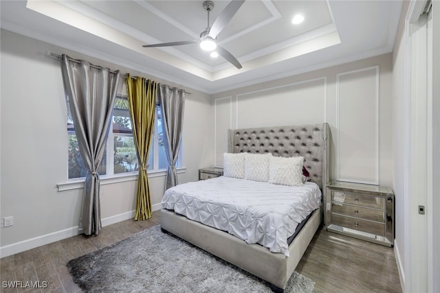 bedroom featuring crown molding, wood-type flooring, a raised ceiling, and ceiling fan