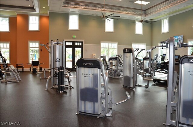 gym featuring a towering ceiling, a raised ceiling, and ceiling fan