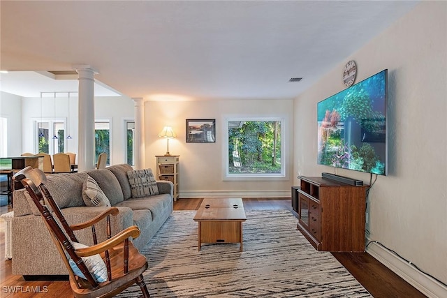 living room with dark hardwood / wood-style flooring, plenty of natural light, and decorative columns