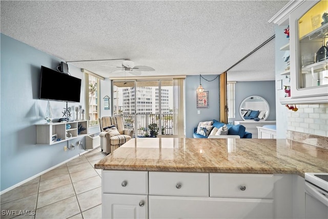 kitchen with ceiling fan, light tile patterned floors, a textured ceiling, white cabinets, and open floor plan