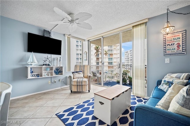 tiled living area featuring a wall of windows, a textured ceiling, baseboards, and a ceiling fan