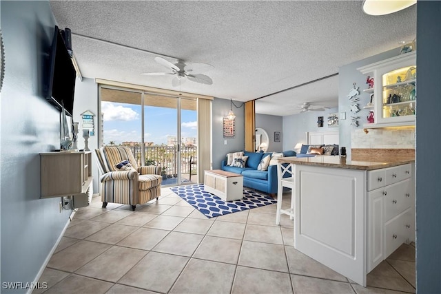 living area with a wall of windows, ceiling fan, a textured ceiling, and light tile patterned floors