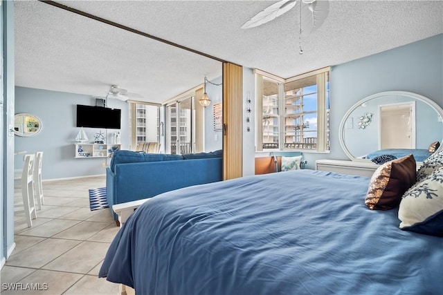 bedroom with baseboards, tile patterned flooring, a ceiling fan, and a textured ceiling