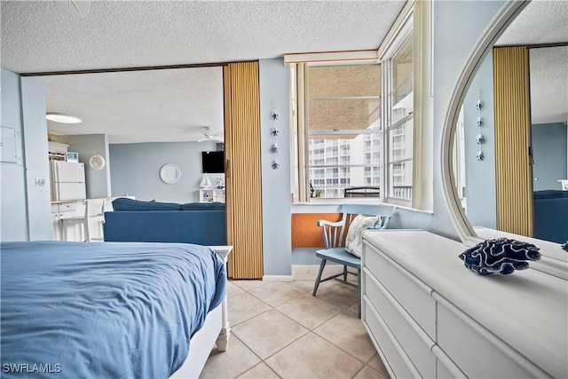 bedroom featuring freestanding refrigerator, light tile patterned flooring, and a textured ceiling