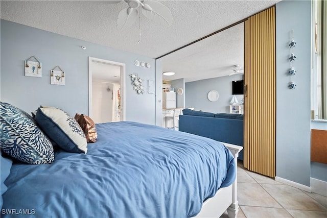 bedroom featuring light tile patterned floors, baseboards, a ceiling fan, and a textured ceiling