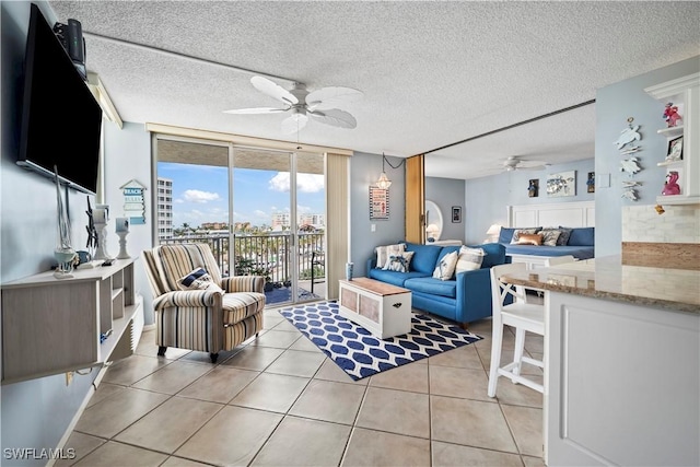 living room with light tile patterned floors, a textured ceiling, a ceiling fan, floor to ceiling windows, and a view of city