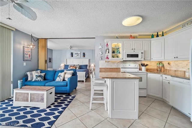 7300 Estero Blvd Unit 308, Fort Myers Beach, FL 33931 - kitchen featuring white appliances, ceiling fan, white cabinetry, a kitchen breakfast bar, and a sink