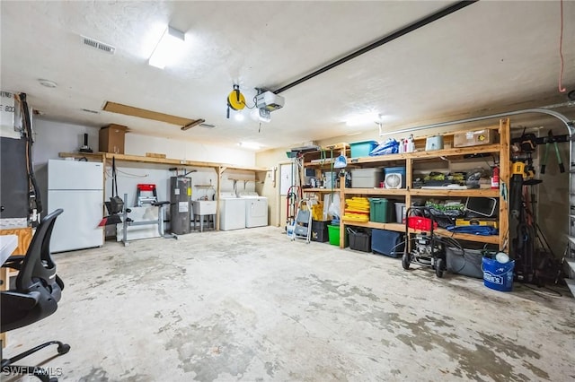 garage featuring washer and clothes dryer, electric water heater, a garage door opener, white refrigerator, and sink