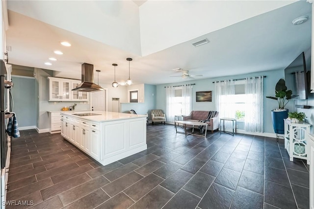 kitchen featuring hanging light fixtures, a kitchen island with sink, white cabinets, island range hood, and black electric cooktop