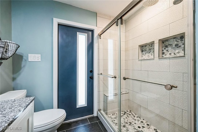 bathroom with walk in shower, vanity, toilet, and tile patterned flooring