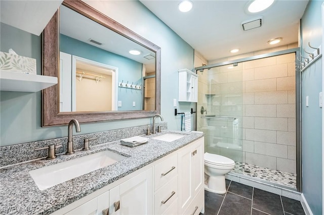 bathroom featuring toilet, tile patterned flooring, a shower with shower door, and vanity