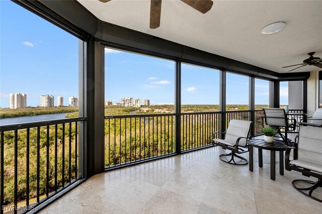 sunroom with a water view, ceiling fan, and a healthy amount of sunlight