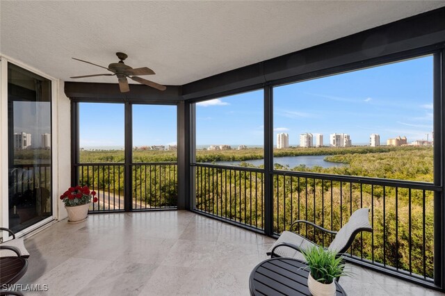 sunroom / solarium with a water view, plenty of natural light, and ceiling fan