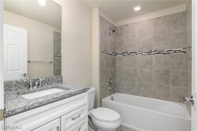 full bathroom featuring tiled shower / bath, vanity, and toilet