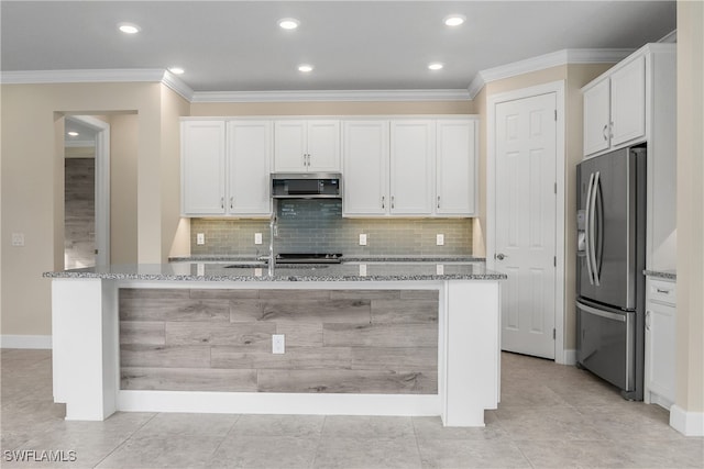 kitchen with light stone countertops, stainless steel appliances, white cabinetry, and a kitchen island with sink