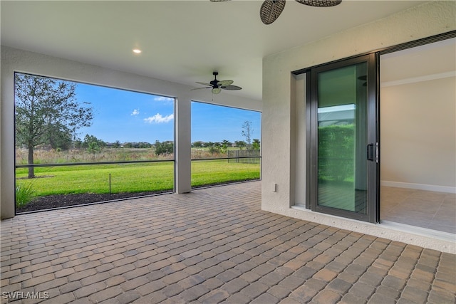 unfurnished sunroom featuring ceiling fan