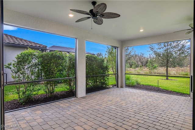 unfurnished sunroom featuring ceiling fan