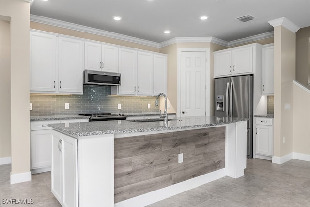 kitchen featuring appliances with stainless steel finishes, an island with sink, sink, white cabinets, and light stone countertops