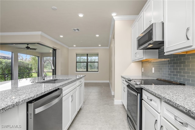 kitchen featuring stainless steel appliances, white cabinetry, sink, and light stone counters