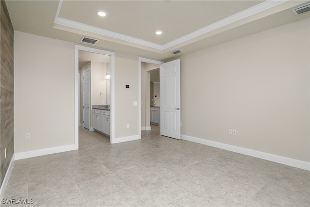 unfurnished bedroom featuring crown molding, ensuite bathroom, and a tray ceiling