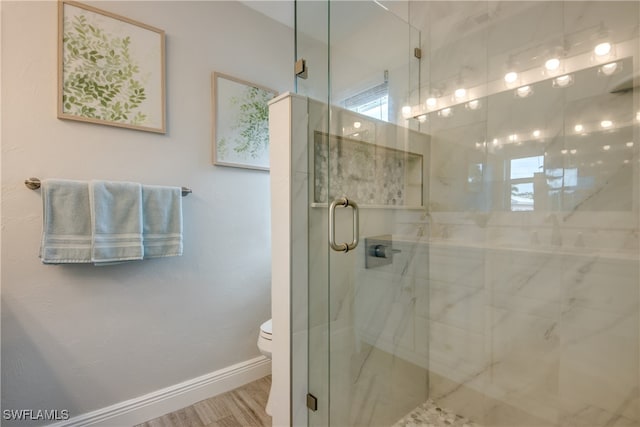 bathroom with toilet, a shower with shower door, and hardwood / wood-style floors