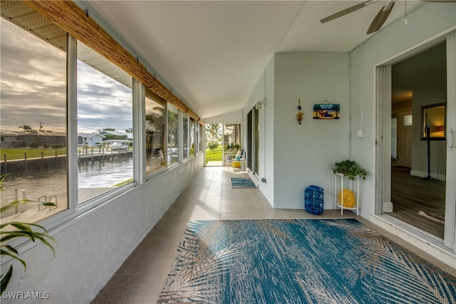 unfurnished sunroom with ceiling fan and a water view