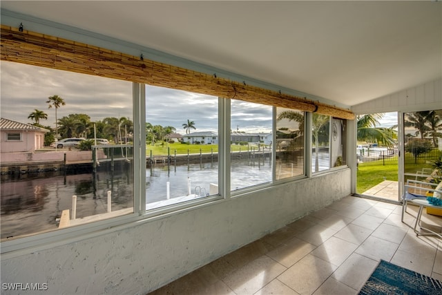 unfurnished sunroom featuring lofted ceiling and a water view