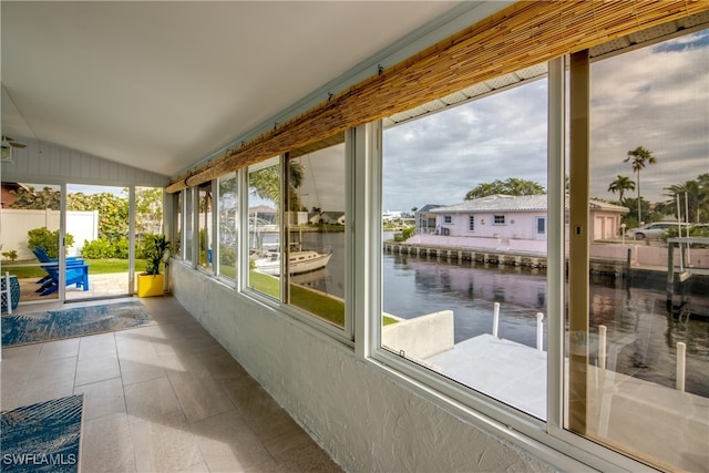 sunroom / solarium featuring a water view and vaulted ceiling