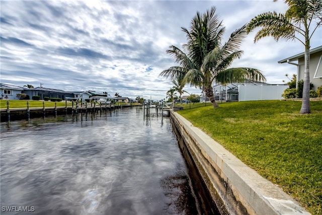 view of dock featuring a lawn and a water view