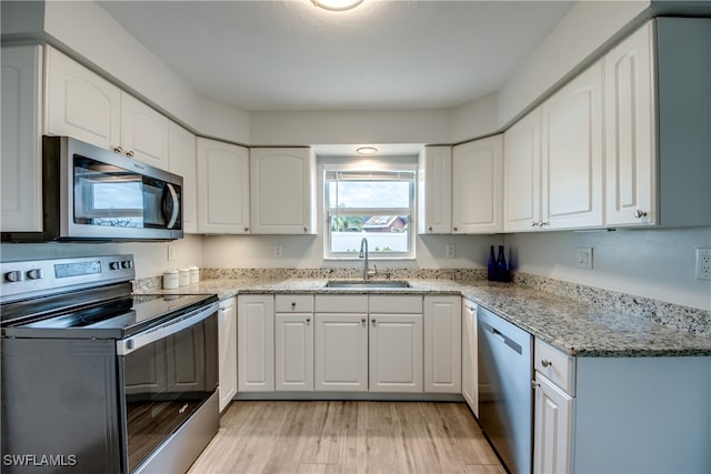 kitchen featuring appliances with stainless steel finishes, sink, light stone counters, and white cabinetry