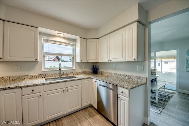 kitchen featuring stainless steel dishwasher, white cabinets, sink, and light stone counters