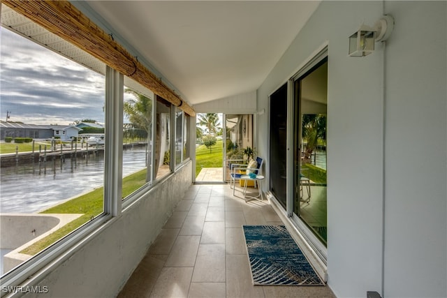 unfurnished sunroom featuring a water view and lofted ceiling