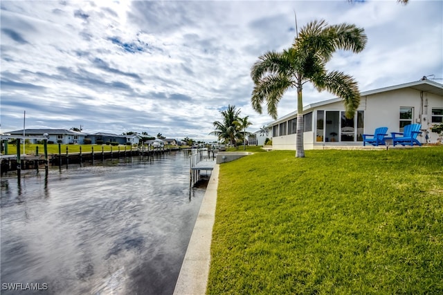 view of dock featuring a lawn and a water view