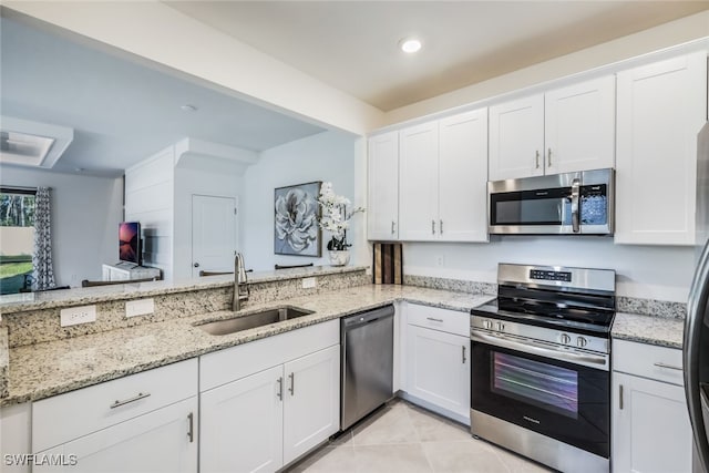 kitchen with white cabinetry, sink, light tile patterned floors, stainless steel appliances, and light stone countertops