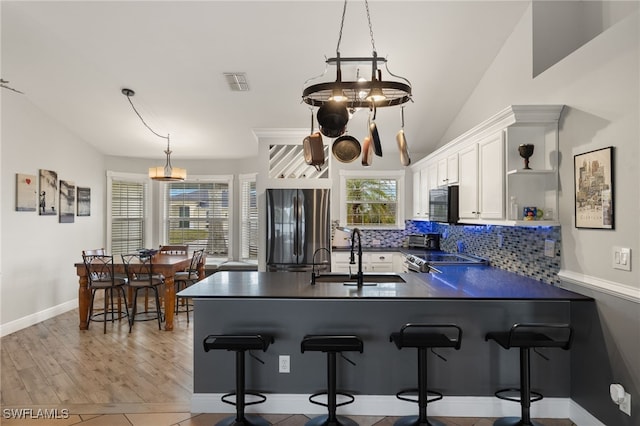 kitchen with a chandelier, stainless steel appliances, white cabinets, backsplash, and sink