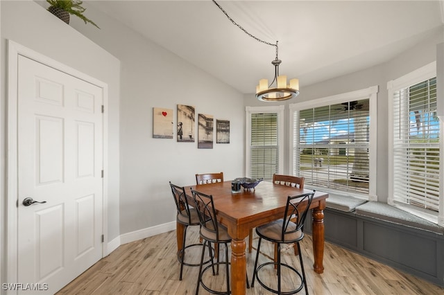 dining area with light hardwood / wood-style floors, a notable chandelier, and lofted ceiling