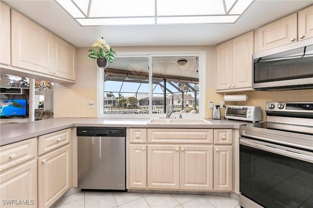 kitchen with light tile patterned floors, sink, decorative backsplash, and appliances with stainless steel finishes