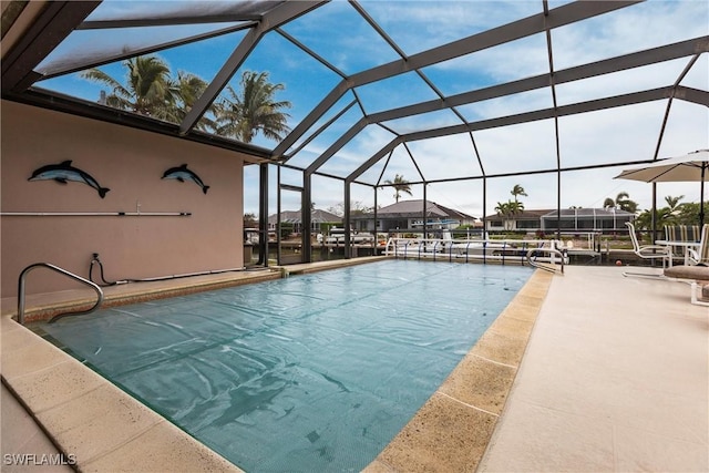 view of swimming pool featuring glass enclosure, a patio area, and a water view