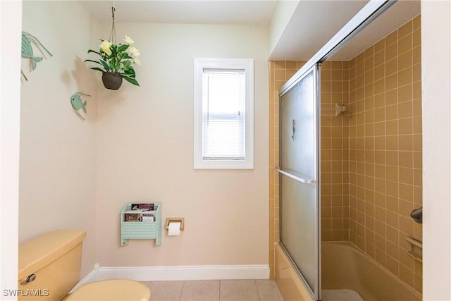 bathroom featuring toilet, combined bath / shower with glass door, and tile patterned floors