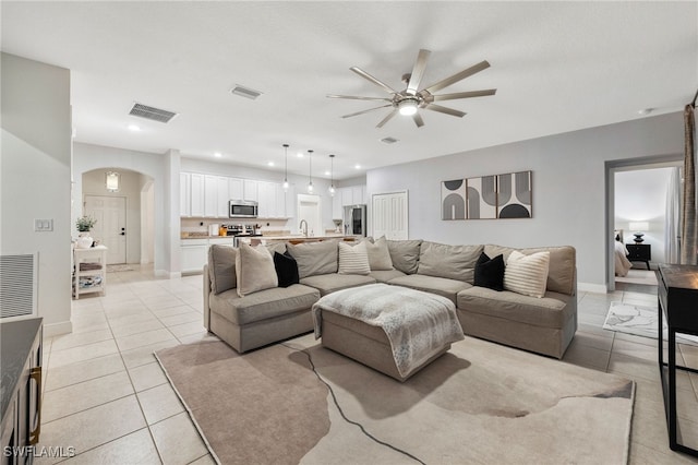 tiled living room featuring ceiling fan and sink