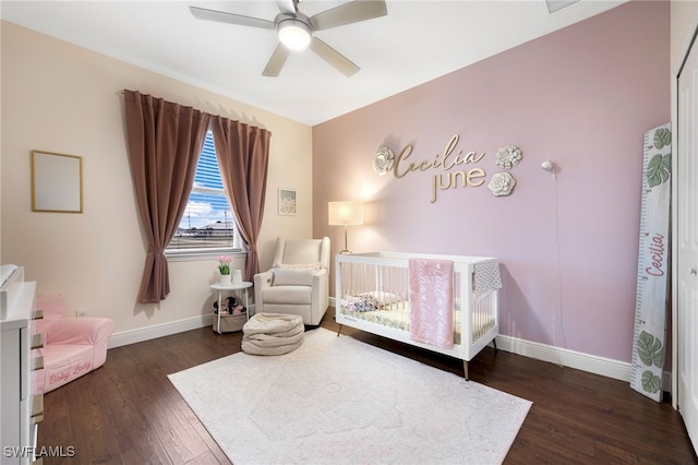 bedroom featuring ceiling fan, dark hardwood / wood-style flooring, and a nursery area