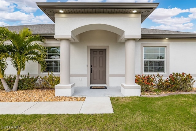 view of exterior entry with a yard