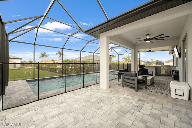 view of patio / terrace featuring glass enclosure, ceiling fan, an outdoor kitchen, a fenced in pool, and outdoor lounge area