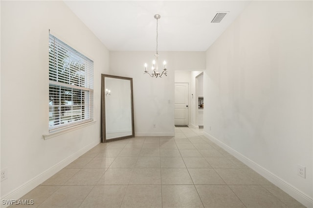 spare room featuring an inviting chandelier and light tile patterned floors