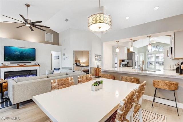 dining area featuring ceiling fan, lofted ceiling, light hardwood / wood-style flooring, and sink