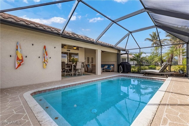 view of pool featuring ceiling fan, an outdoor living space, a patio, and glass enclosure