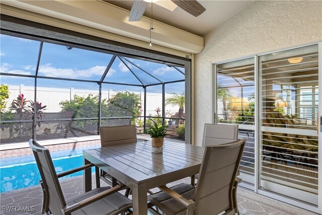 sunroom with ceiling fan, plenty of natural light, and lofted ceiling