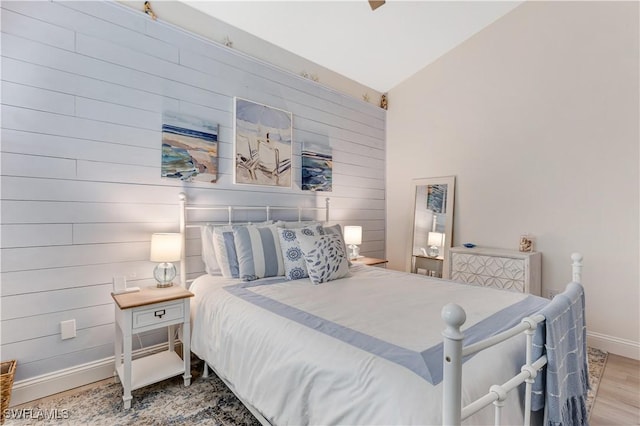 bedroom featuring ceiling fan, vaulted ceiling, wood walls, and wood-type flooring