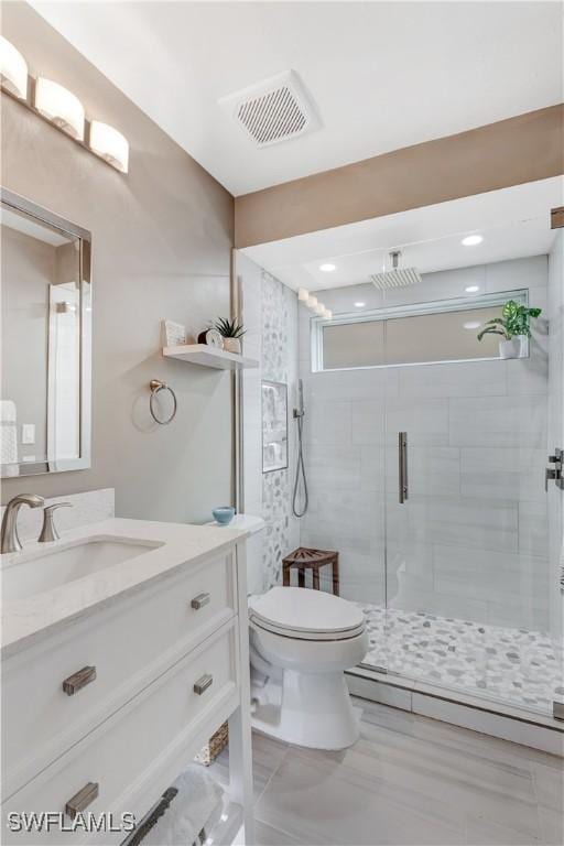 bathroom featuring an enclosed shower, vanity, and toilet