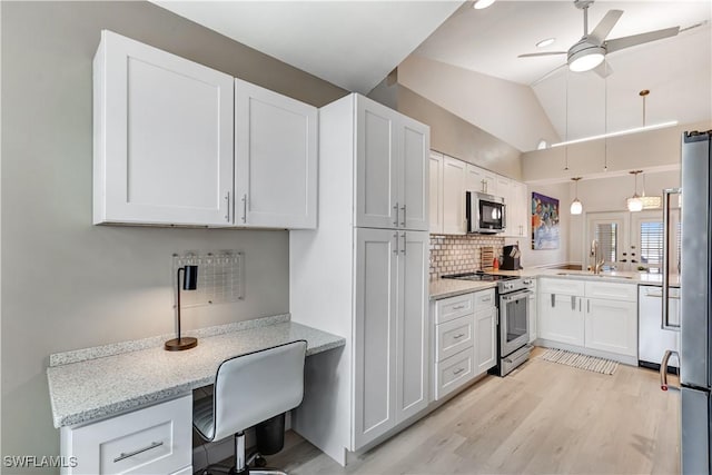 kitchen with appliances with stainless steel finishes, tasteful backsplash, light stone countertops, vaulted ceiling, and white cabinets